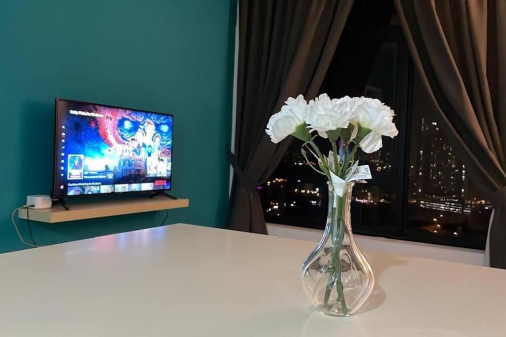 un vase de fleurs blanches sur une table avec une télévision dans l'établissement KB22, Cyberjaya, Netflix, WiFi, Free Parking, 1010, à Cyberjaya
