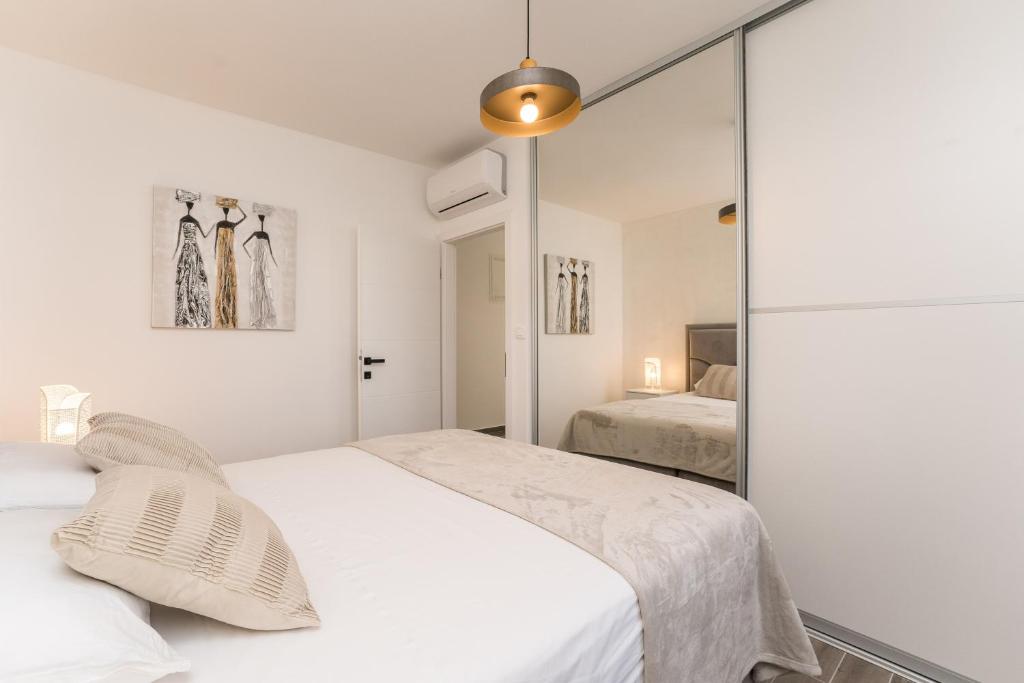 a white bedroom with two beds and a mirror at Luxury D Apartments in Bibinje