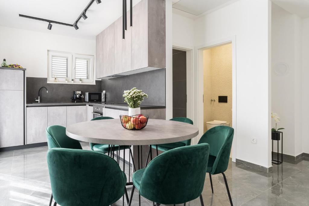 a kitchen and dining room with a table and green chairs at Luxury D Apartments in Bibinje