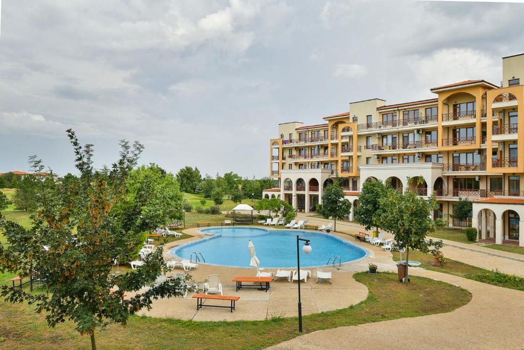 an apartment complex with a swimming pool in front of a building at Lighthouse Golf Apart Complex&Villas in Balchik