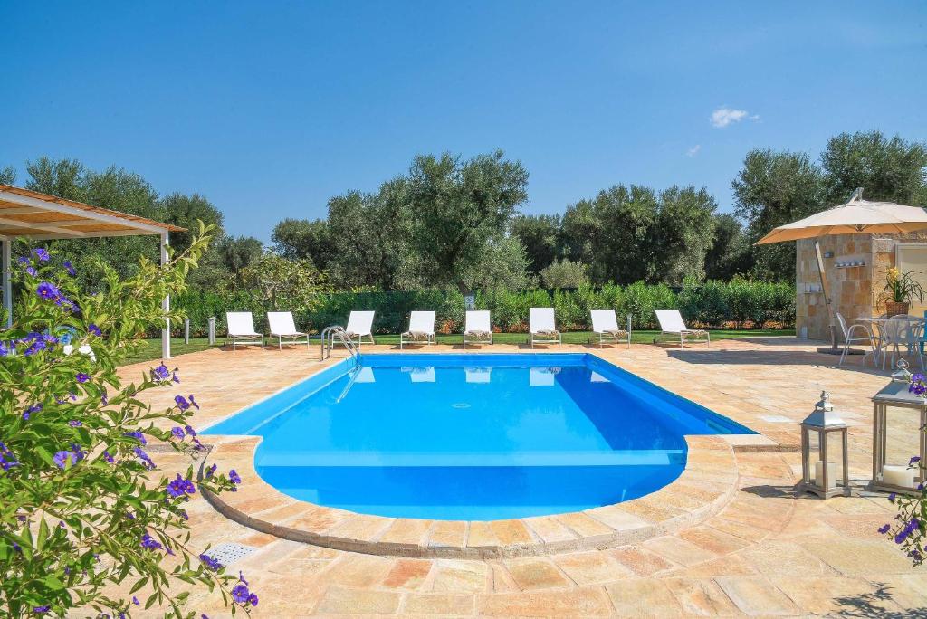 - une piscine dans une cour avec des chaises et un parasol dans l'établissement Villa Theros by Perle di Puglia, à San Michele Salentino