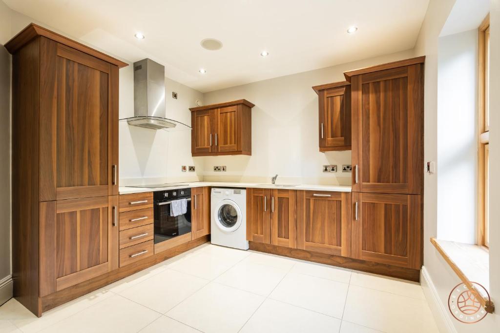 a kitchen with wooden cabinets and a washer and dryer at Escape Ordinary at Castle Hume in Enniskillen