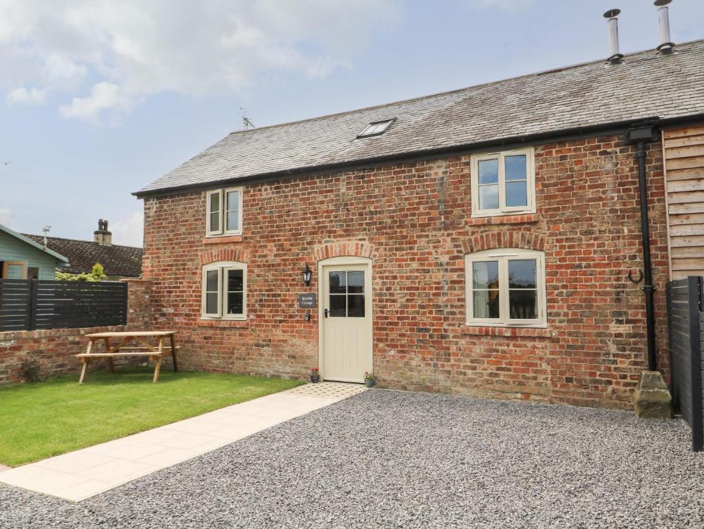 a brick house with a white door and a bench at Spindle Cottage in York