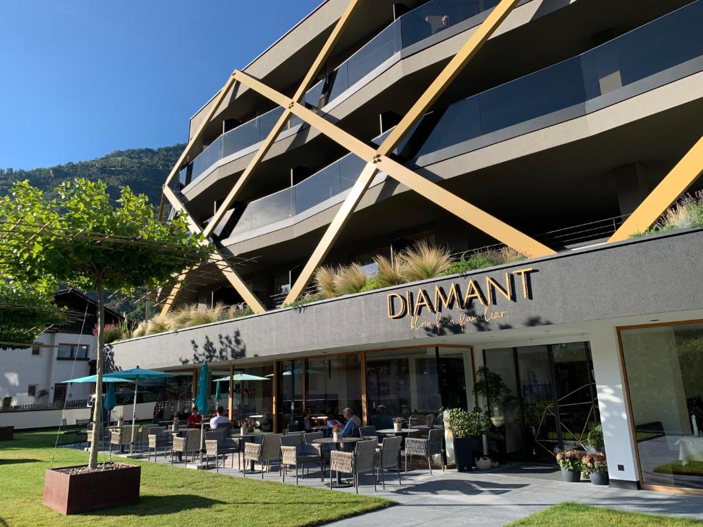 un bâtiment avec des tables et des chaises devant lui dans l'établissement Genusshotel Diamant, à Naturno