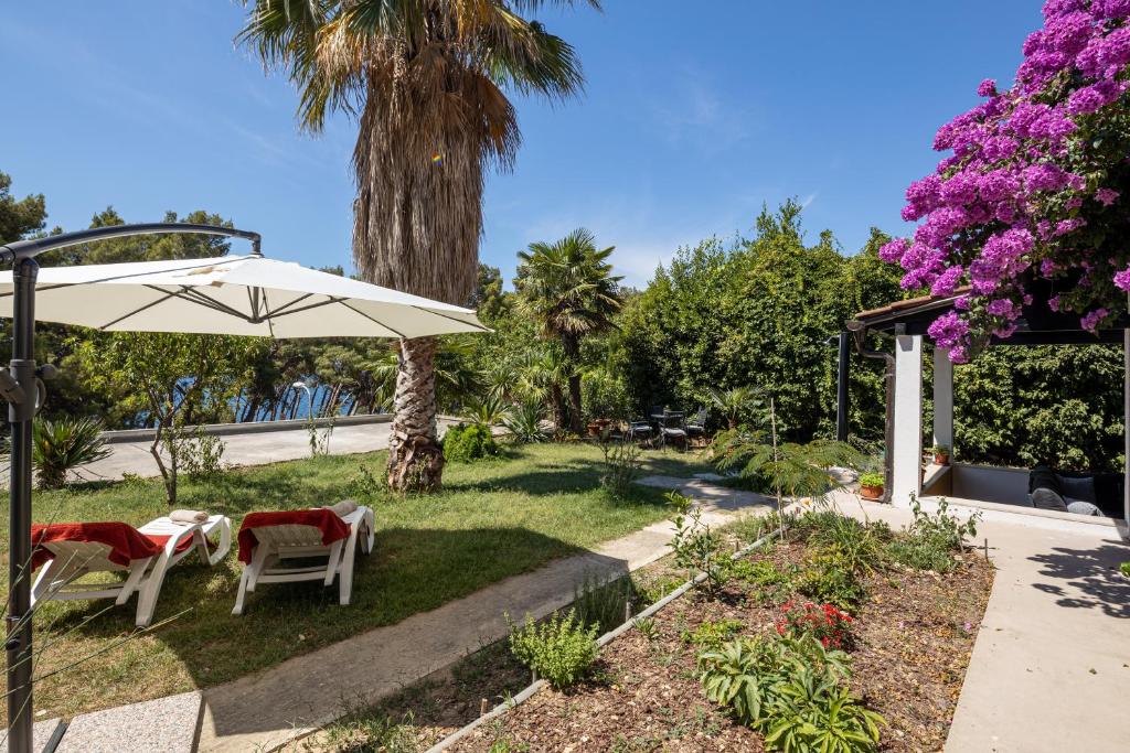 a garden with two chairs and an umbrella at Sea View & Beach Luxury Palm Garden Split Apartment in Split