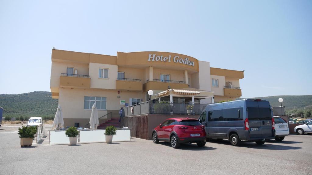 a hotel building with a van parked in a parking lot at Hotel godisa in Argamasilla de Calatrava