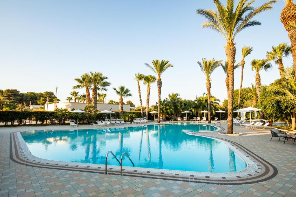 a large swimming pool with palm trees in a resort at Giardino Dei Pini in Alliste