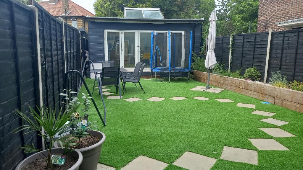 a small garden with green grass and a patio at Stunning 1-Bed Cabin in Bromley with hot tub in Bromley