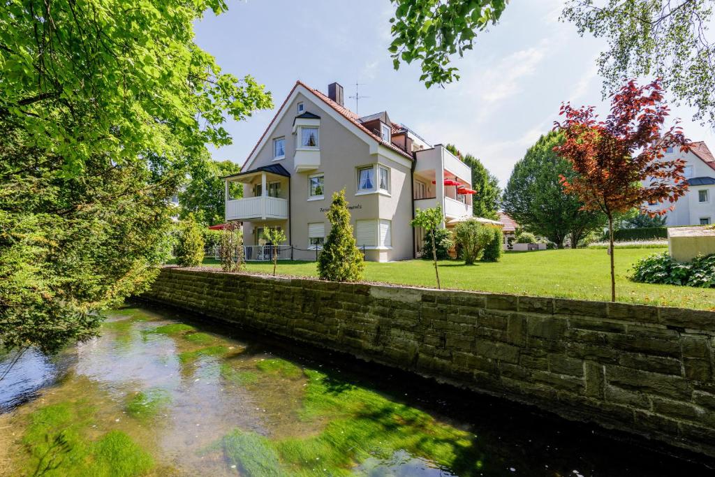 a house with a stone wall next to a river at Haus am Mühlenweg - Appartement 4 Haus I - sonniges und modernes Ferienappartement in Bad Wörishofen