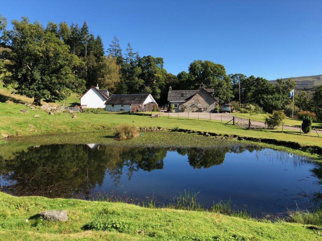 a pond in a field with houses in the background at Ardgarry Farm in Invergarry
