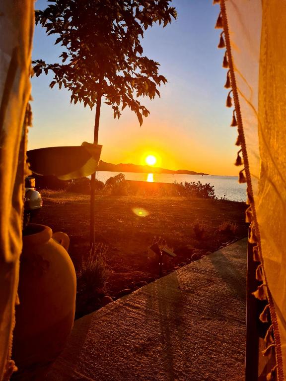 un coucher de soleil à travers une fenêtre avec vue sur l'océan dans l'établissement Le Panoramic, à Saint-Florent