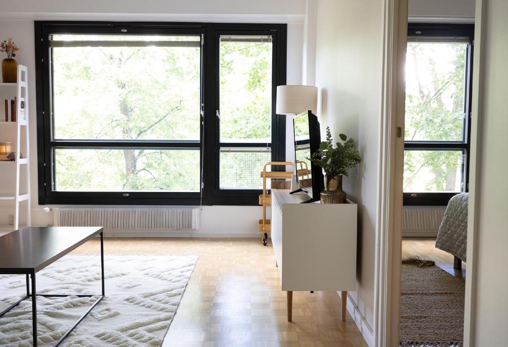 a living room with two large windows and a table at 2ndhomes City Center 2BR Kaisaniemi Park Apartment with Balcony in Helsinki