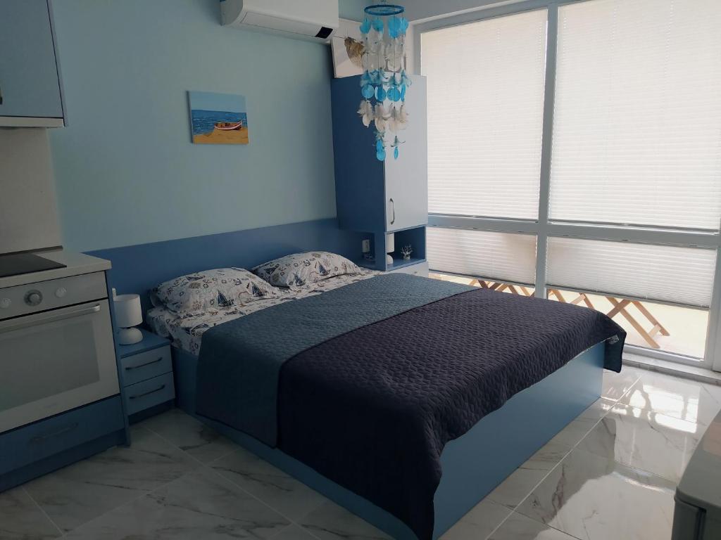 Dormitorio azul con cama y ventana en Апартамент Blue apartment, гр. Китен, en Kiten