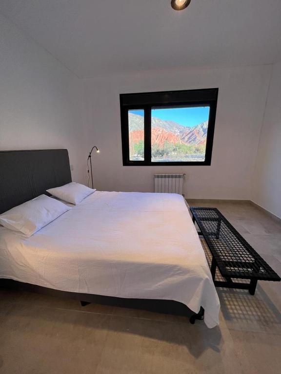 a bedroom with a large white bed and a window at Coquena · Casita con Parrilla y Viñedo in Purmamarca