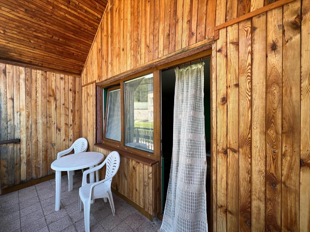 eine Veranda mit einem Tisch, Stühlen und einem Fenster in der Unterkunft Dedinky Lakeview Cottage in Dedinky