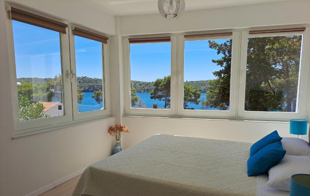 a bedroom with four windows with a view of the water at A2D1 Mali Losinj in Mali Lošinj