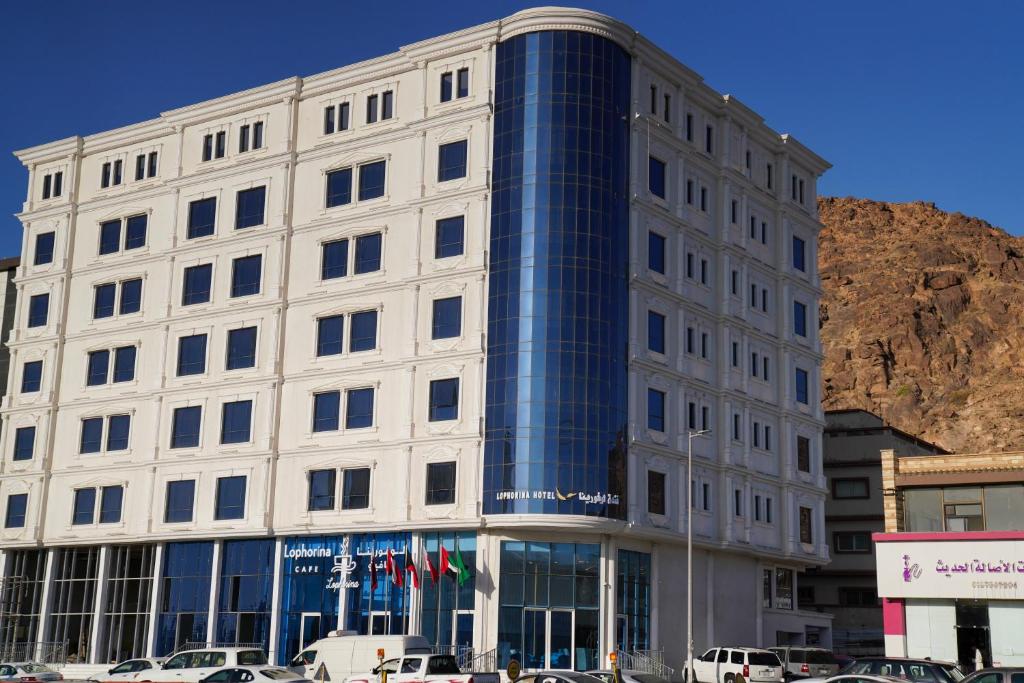 a large white building with a blue window at Lophorina Hotel in Al ‘Abābīd