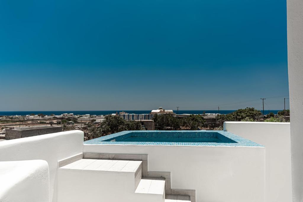 una piscina al lado de un edificio blanco en The Tree Houses Santorini, en Perissa