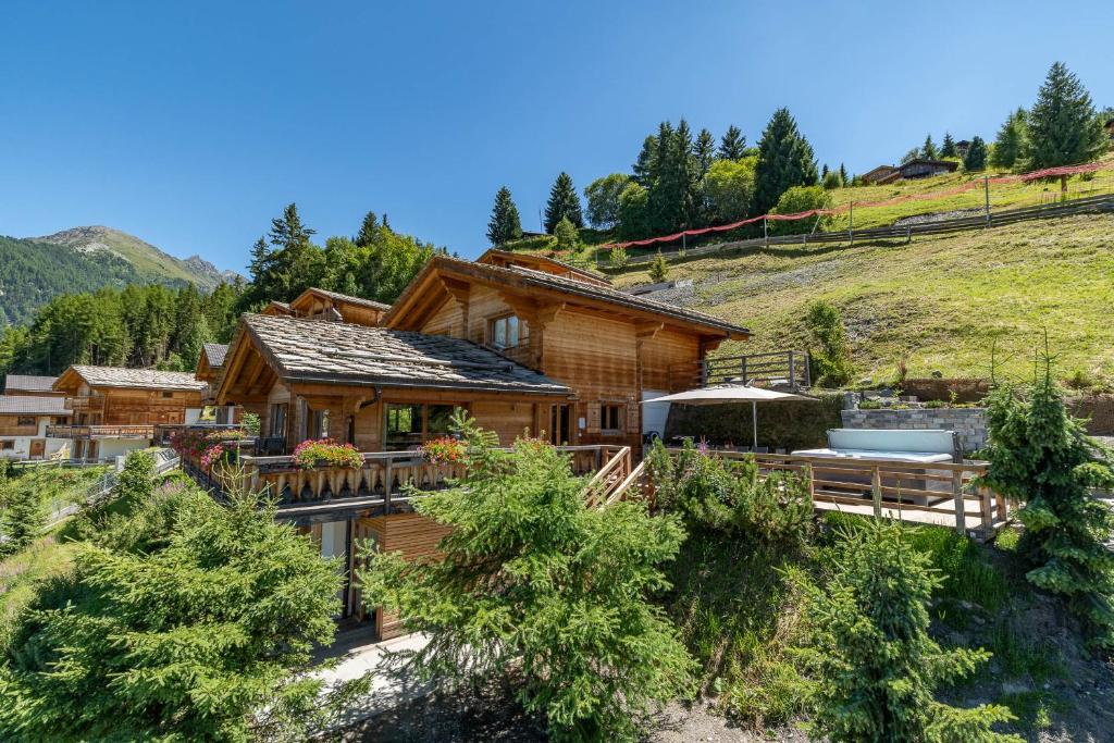 une maison en rondins dans les montagnes avec une terrasse dans l'établissement Chalet le Grand Ours, à La Tzoumaz