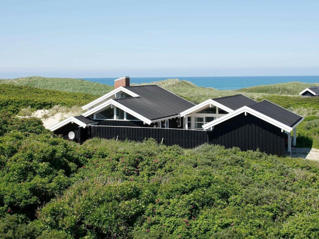 a house on a hill with the ocean in the background at 10 person holiday home in L kken in Grønhøj