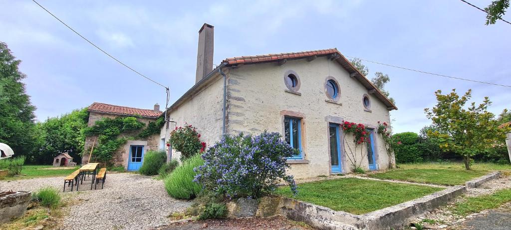 une petite maison blanche avec des fenêtres bleues et des fleurs dans l'établissement Le Terrier maison de campagne 250 m2 grande capacité 20 couchages, 4500m2 de terrain, à Saint-Pierre-du-Chemin