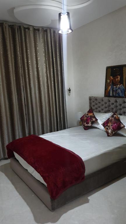 a bedroom with a bed with a red blanket on it at Maison GHITA in Azrou