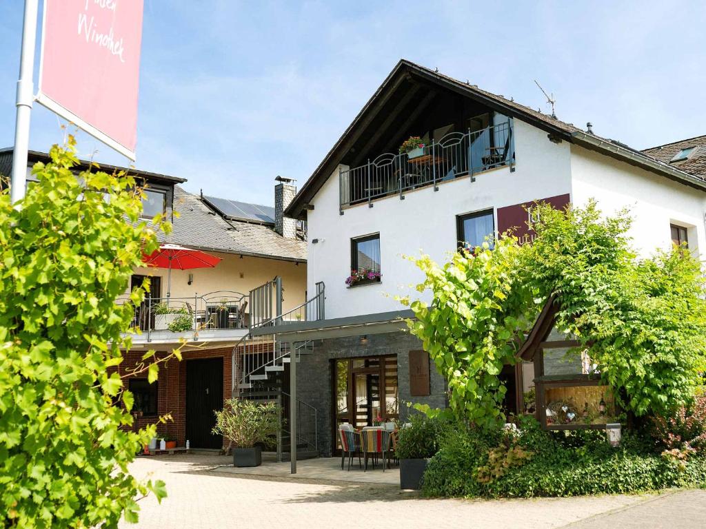 a white building with a balcony and tables and chairs at Wein & Wohngut Paulushof in Pünderich