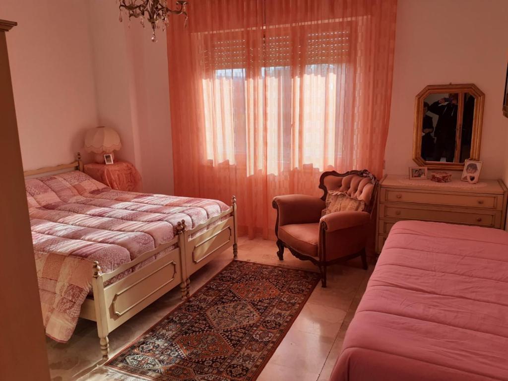 um quarto com 2 camas, uma cadeira e um espelho em B&B ANNA em Piscinas