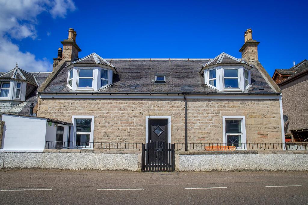 Cosy Cottage in Fishertown, Nairn - Free Parking & Pets welcome! في نيرن: منزل من الطوب مع باب أسود على شارع