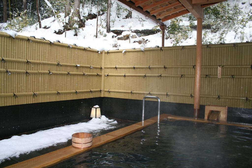 a swimming pool with snow on the ground and a water fountain at Yumoto Onsen OharaSansou in Kyoto