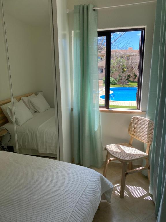 a bedroom with a bed and a window with a view of a pool at Maria Luísa in Olhos de Água