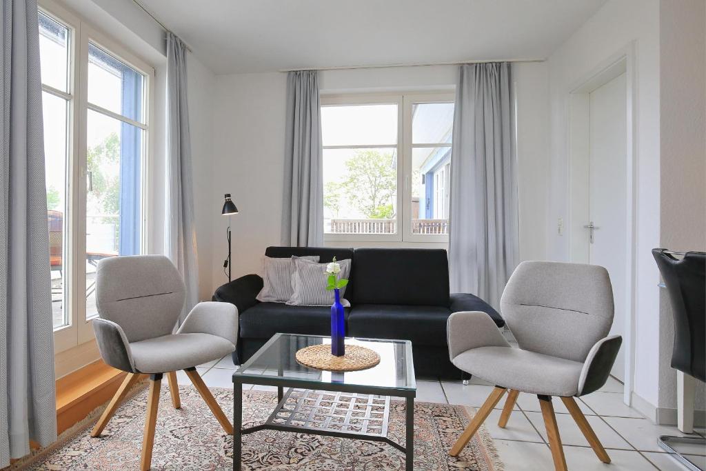 a living room with a couch and two chairs and a table at Dünenblick Wohnung 50 in Boltenhagen