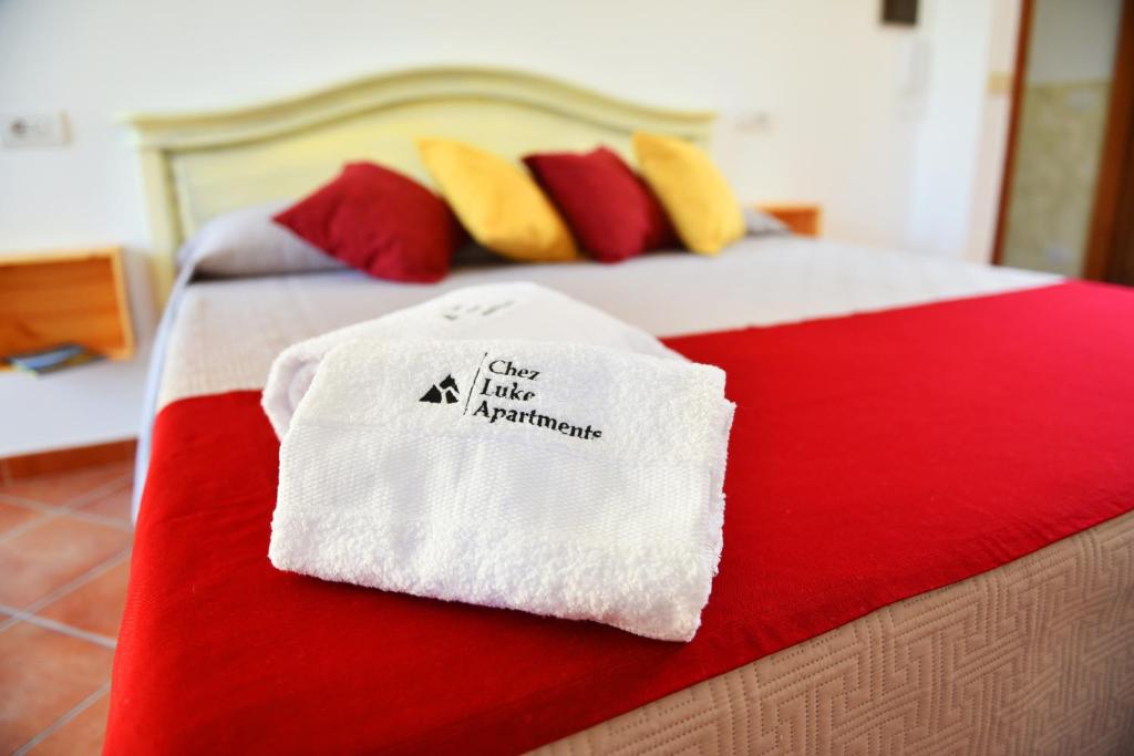 biały ręcznik na łóżku z czerwonymi i żółtymi poduszkami w obiekcie Chez Luke Apartments in Agerola w mieście Agerola
