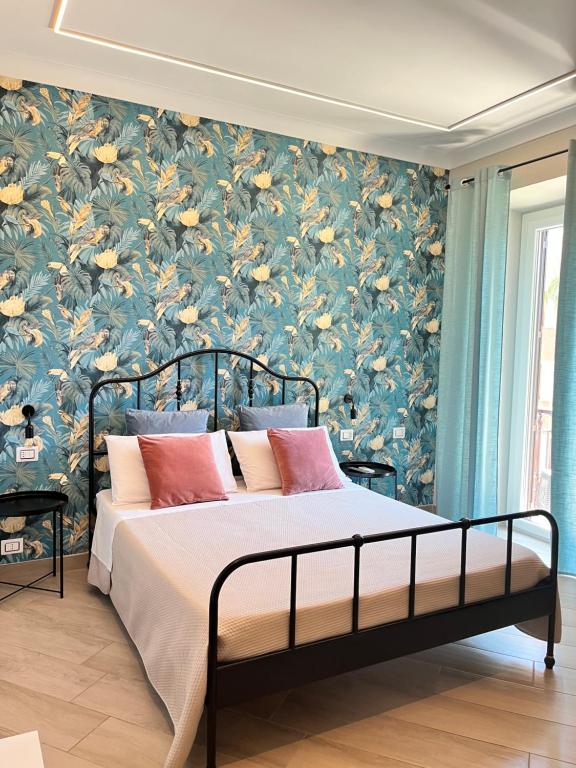 1 dormitorio con 1 cama y papel pintado con motivos florales en B&B Vittoria, en Anzio