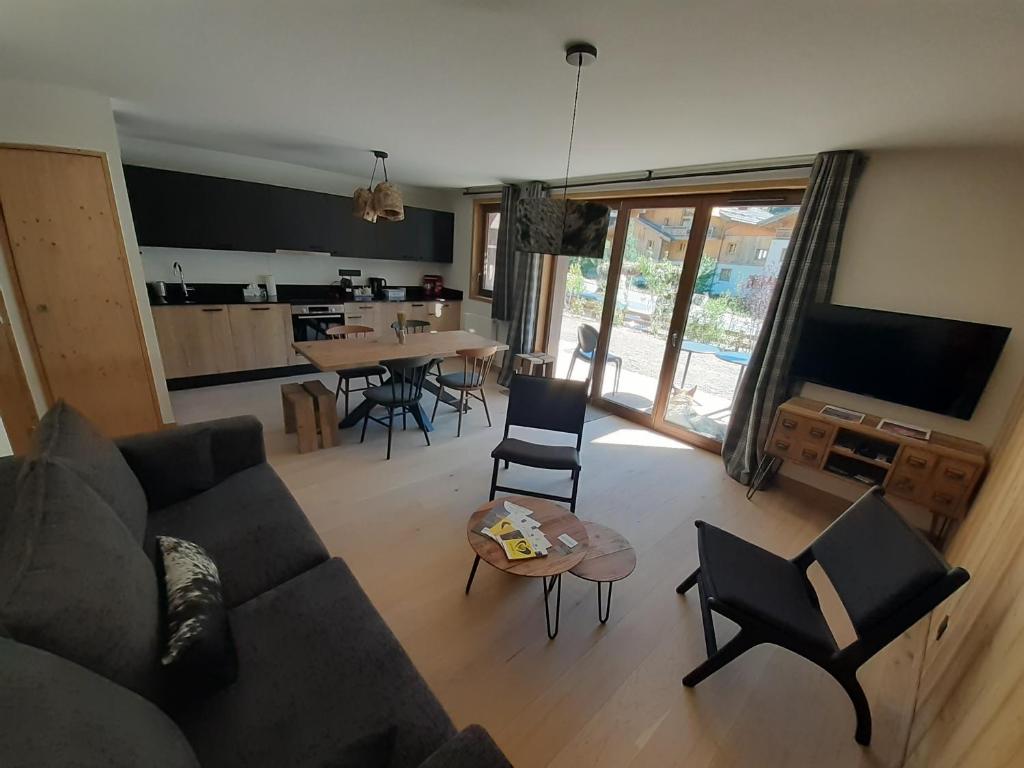 a living room with a couch and a table with chairs at Superbe appartement T3 4 étoiles terrasse accès spa in Saint-Chaffrey