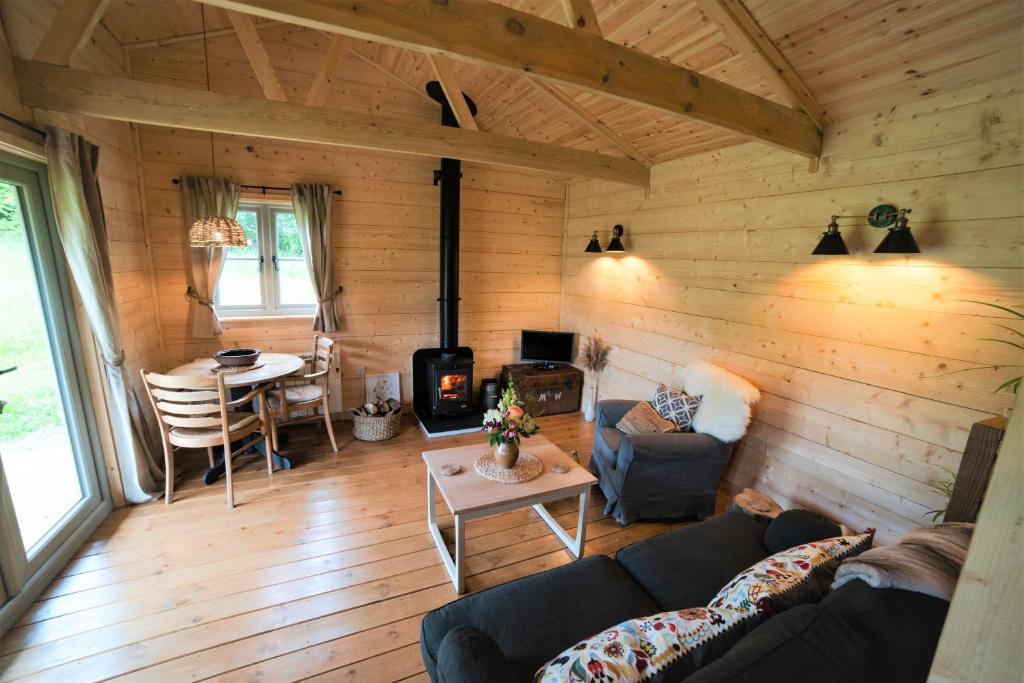 a living room with a couch and a fireplace in a log cabin at Raleigh Lodge in Bideford