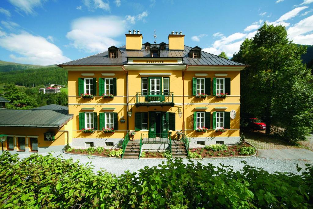 ein großes gelbes Haus mit Balkon darüber in der Unterkunft Villa Solitude in Bad Gastein