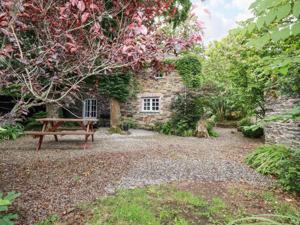 una panchina seduta di fronte a un edificio in pietra di The Cottage a Bodmin