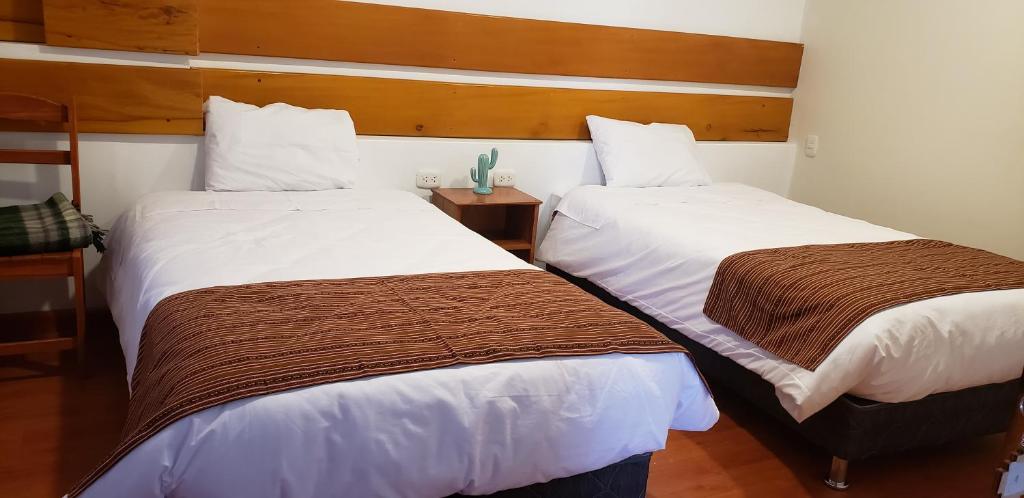duas camas num quarto de hotel com lençóis brancos e castanhos em Tilcafé Bed & Breakfast em Mollepata