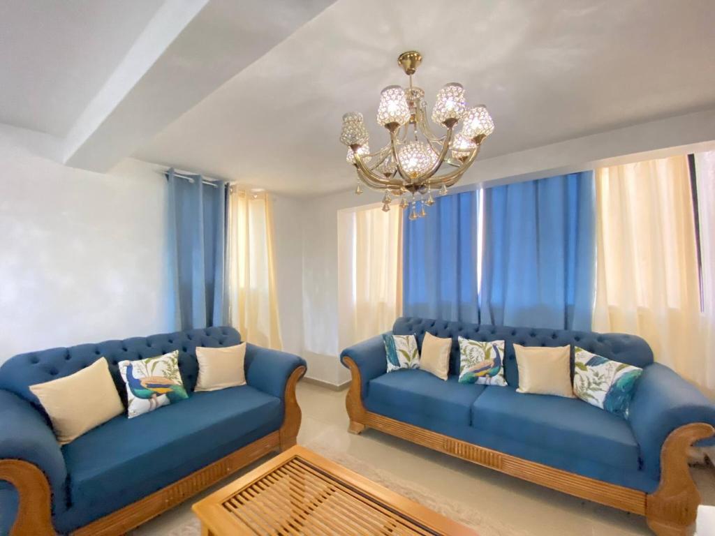 una sala de estar con 2 sofás azules y una lámpara de araña en 8 Adorable Y Comfortable Apt Para Su Disfrute, en Santiago de los Caballeros