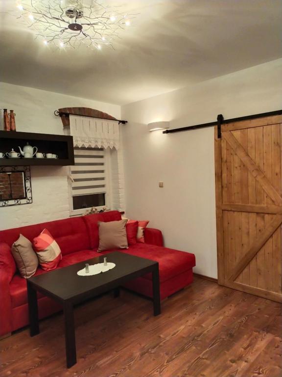 a living room with a red couch and a sliding door at Apartament Sielsko-Wiejsko in Szczytna