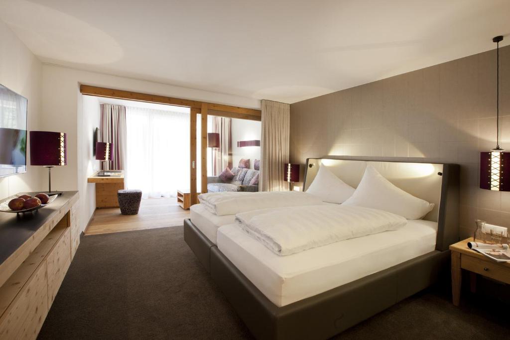 ein Schlafzimmer mit einem großen weißen Bett und ein Wohnzimmer in der Unterkunft Hotel Walliserstube in Damüls