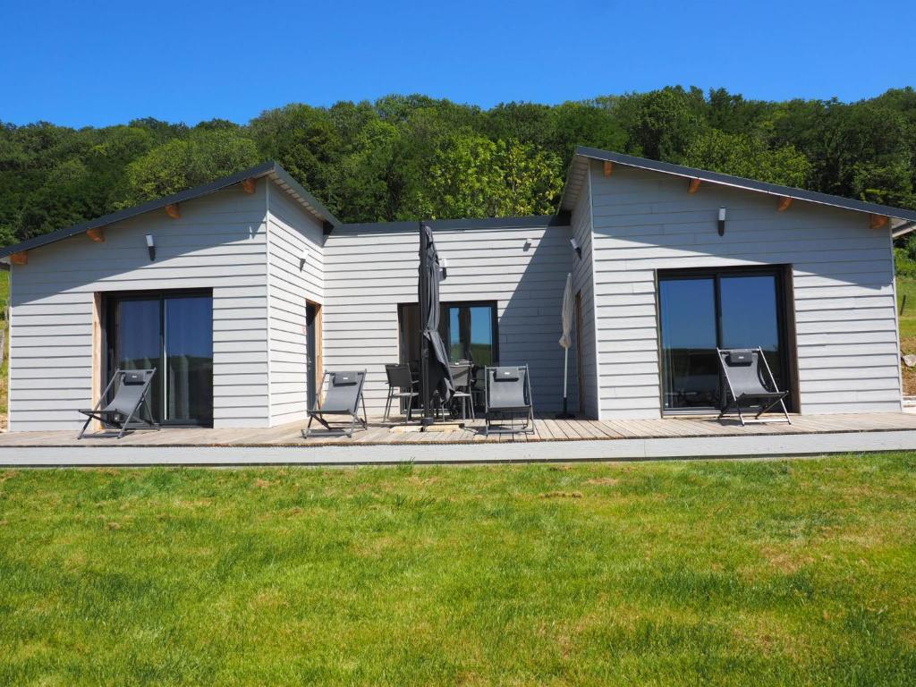 ein Haus mit einer Terrasse mit Stühlen und einem Haus in der Unterkunft Les Lodges du Revermont in Passenans