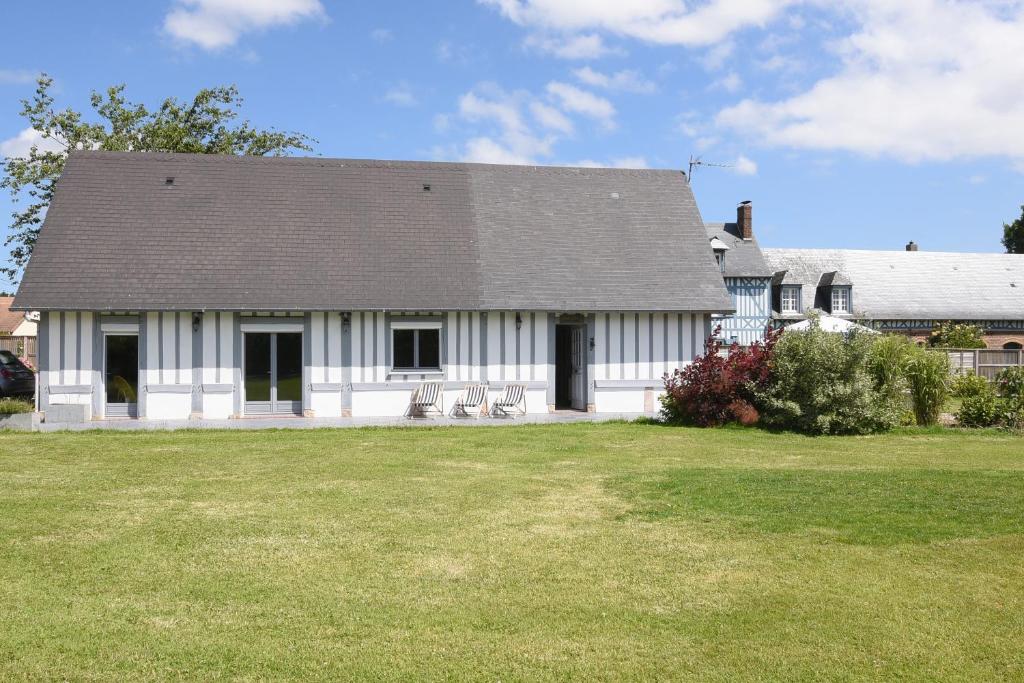 a white house with two chairs in a yard at Le clos Hadrien Maison de campagne in Greuville