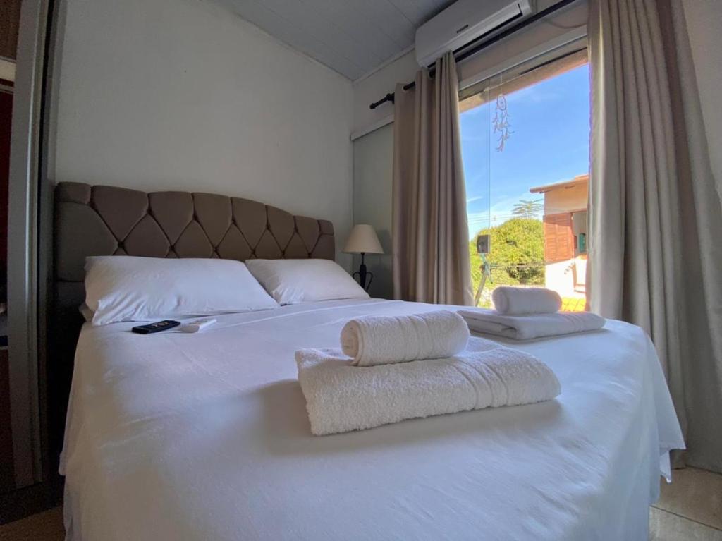 um quarto com uma cama branca e uma grande janela em Casa Aconchego 5min do centro histórico e praia em Paraty