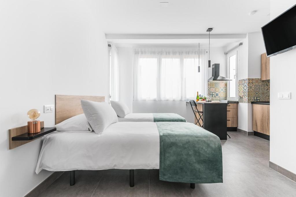 Open Sea Suites في لاس بالماس دي غران كاناريا: غرفة نوم بيضاء مع سرير كبير ومطبخ