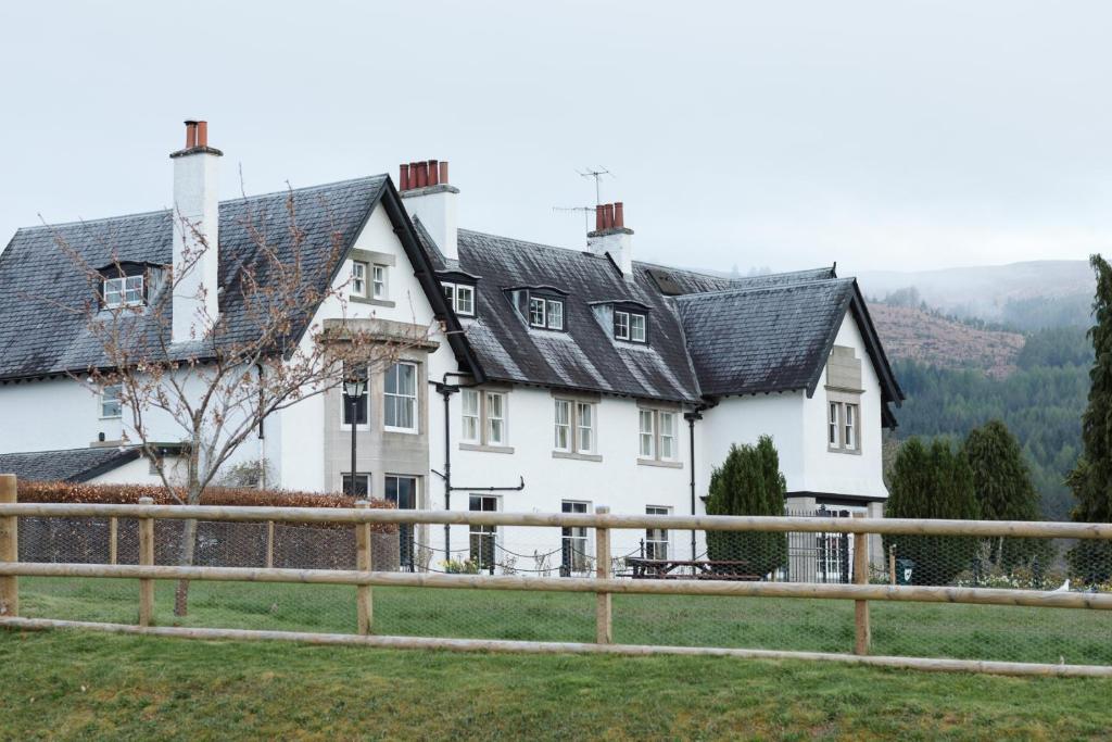 a white house with a fence in front of it at The Lovat, Loch Ness in Fort Augustus