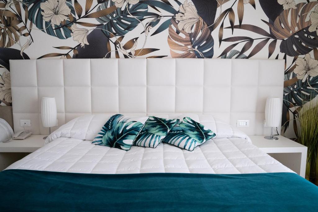 1 dormitorio con cama blanca y almohadas azules en Hotel Conca Verde, en Lignano Sabbiadoro