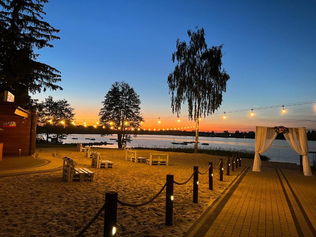 een strand met tafels en stoelen en een lichtje bij Hotel Sanvit Lake Resort & Spa in Okuninka