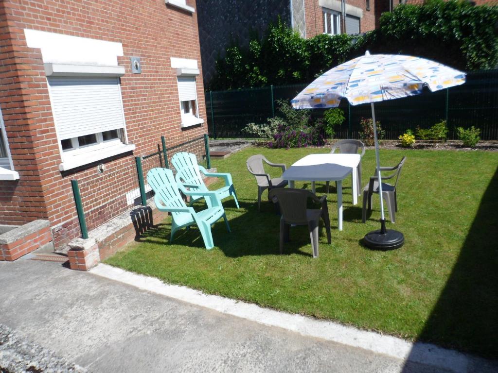 une table, des chaises et un parasol sur une pelouse dans l'établissement Maison individuelle de 100 m2, à Aulnoye-Aymeries
